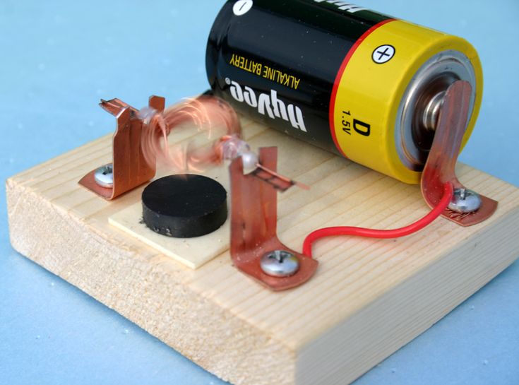 an electric device is connected to a battery on a wooden board with wires and magnets