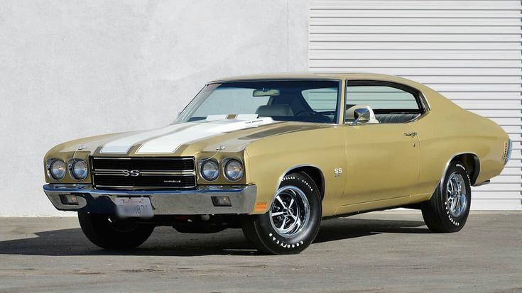 an old muscle car parked in front of a garage