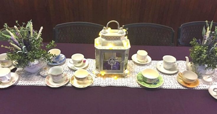 the table is set with tea cups, saucers, and other things on it