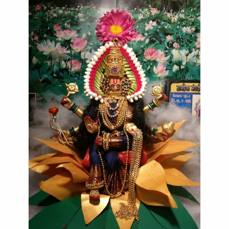 an idol is displayed in front of a floral wallpapered background with pink flowers