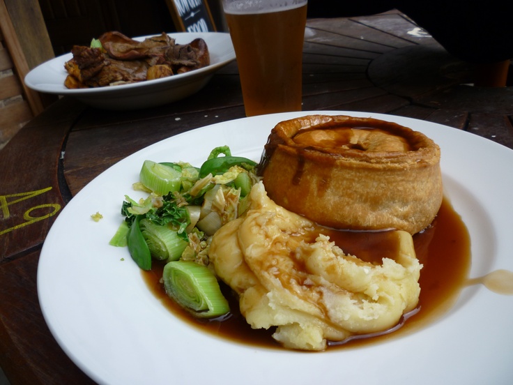 a white plate topped with food next to a glass of beer