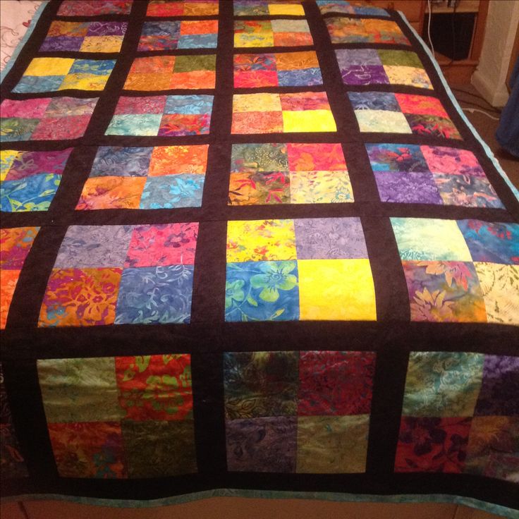 a bed with a colorful quilt on top of it