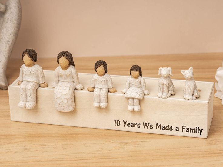 a family figurine sitting on top of a wooden box with the words 10 years we made a family