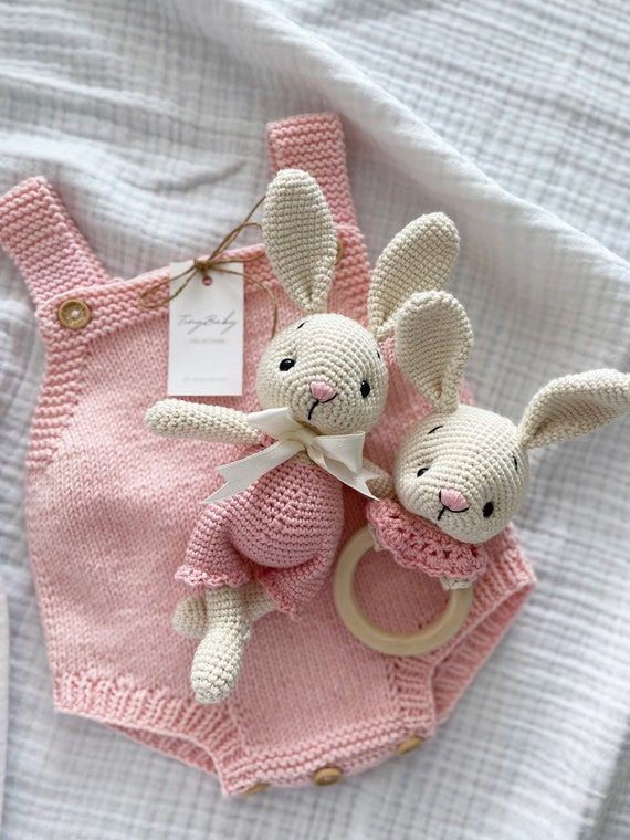 two knitted stuffed animals sitting on top of a pink blanket next to each other