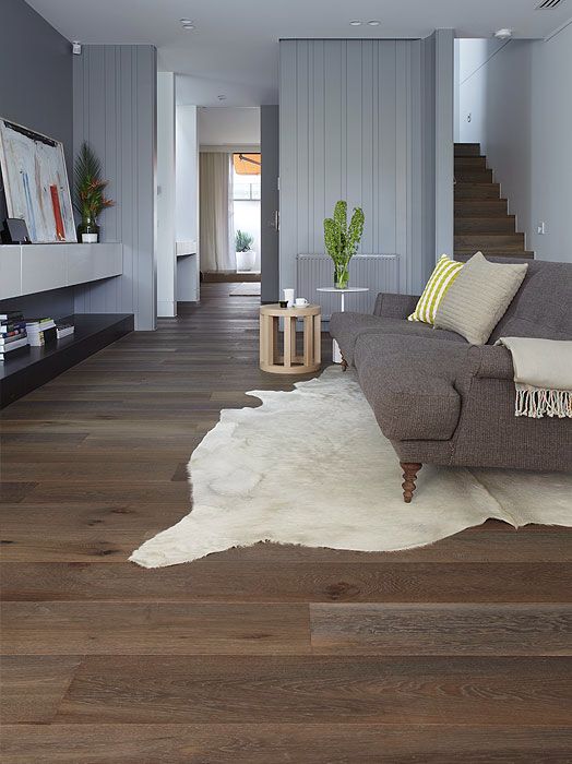 a living room filled with furniture and a white cowhide rug on top of a hard wood floor