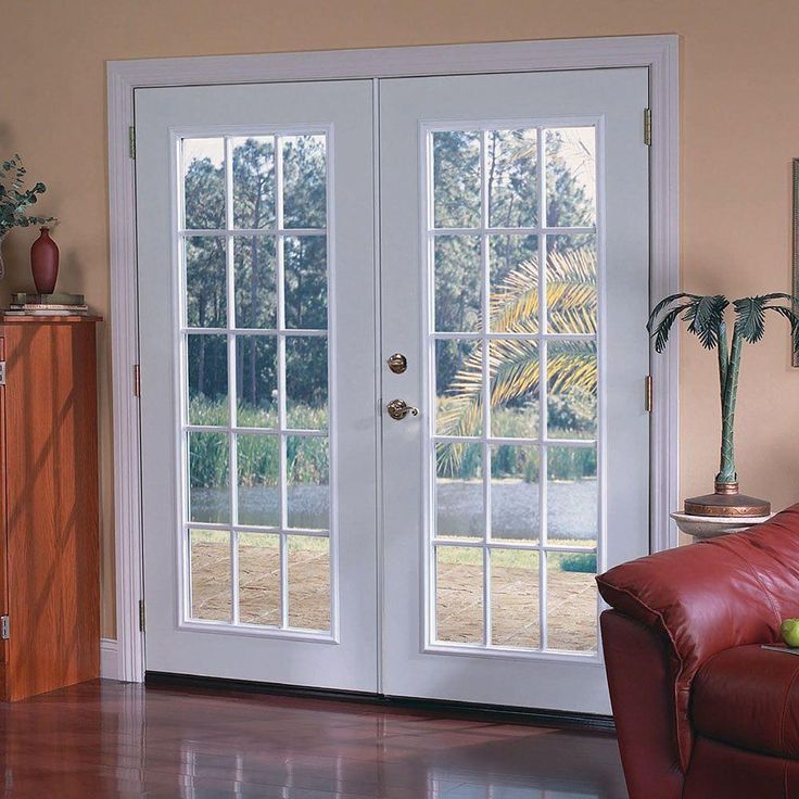 a living room filled with furniture and two french doors leading to the outside patio area