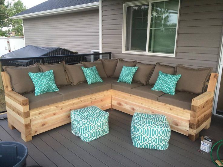 a couch sitting on top of a wooden deck next to a chair and ottomans