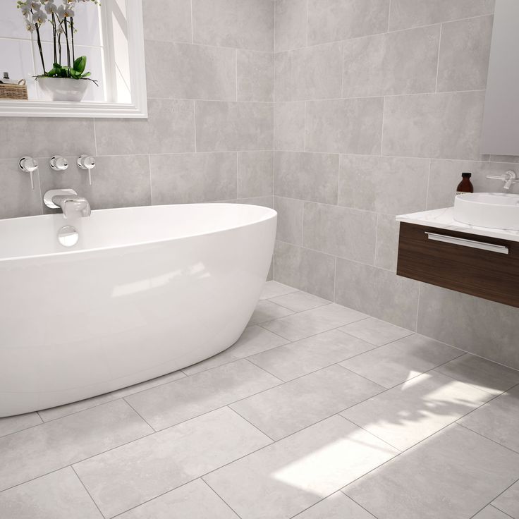 a white bath tub sitting in a bathroom next to a sink and mirror on the wall