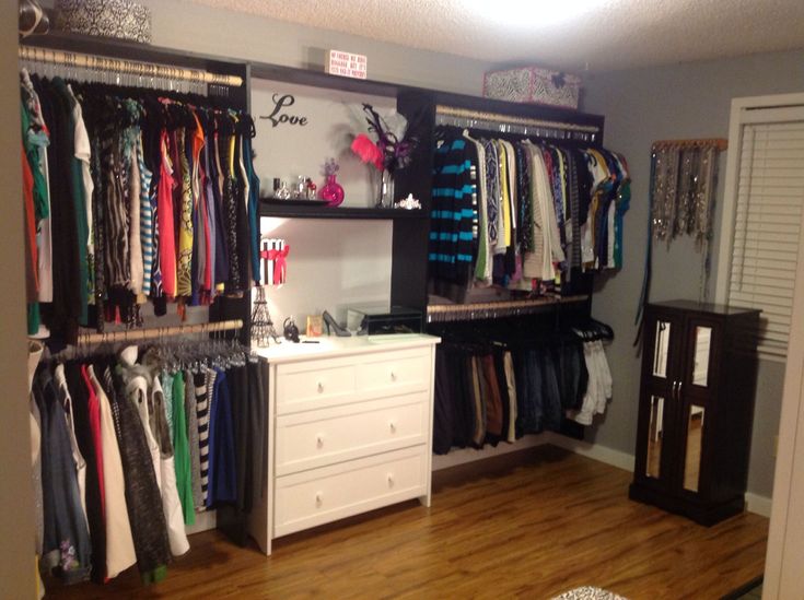 an organized closet with clothes hanging on shelves and drawers in front of the closet door