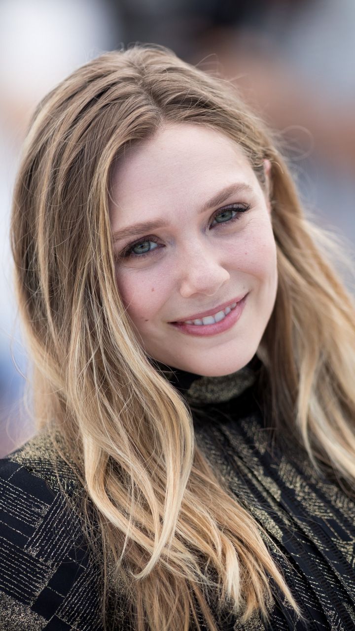 a woman with long blonde hair smiling at the camera