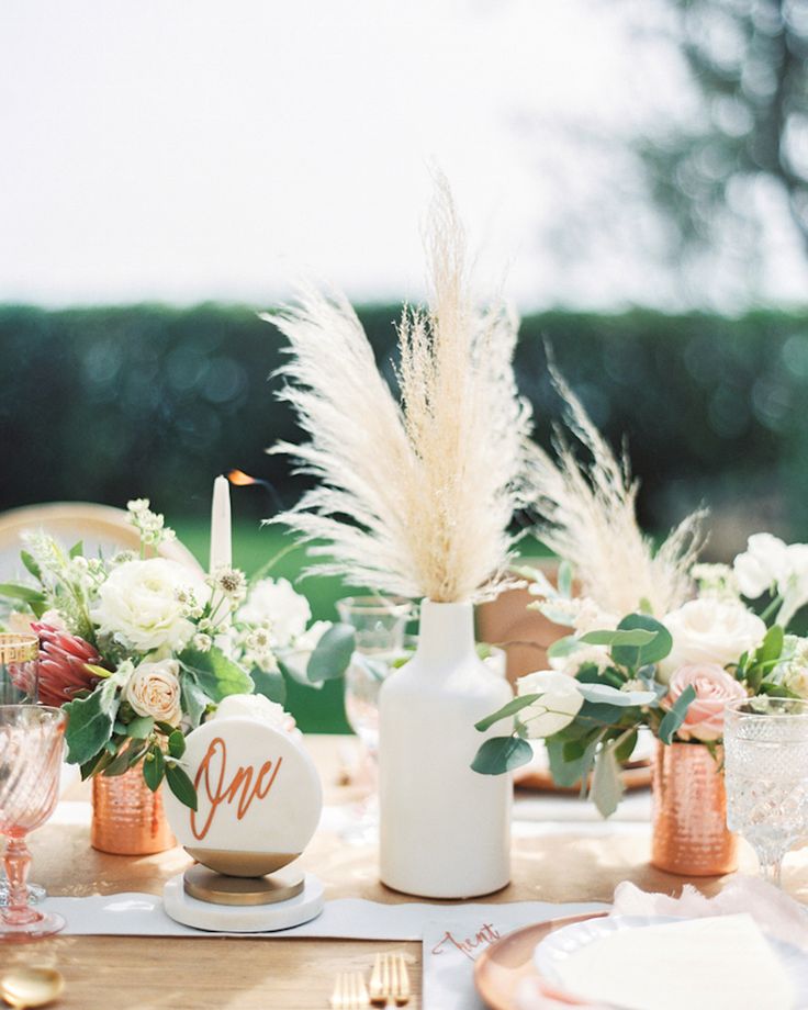 the table is set with white flowers and gold place settings for an elegant dinner party