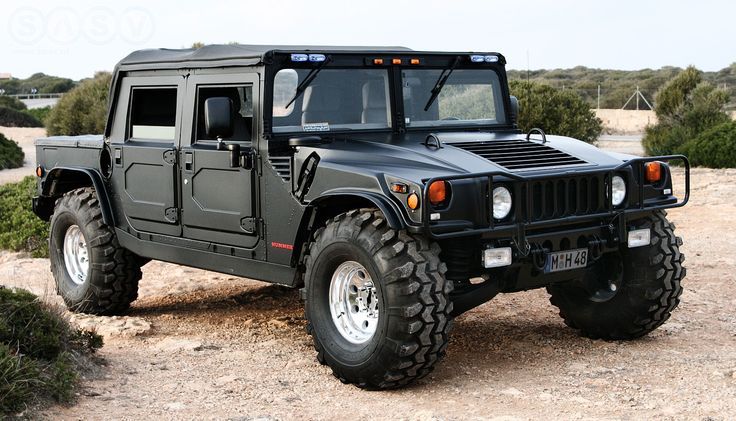 a black hummer truck parked on top of a dirt field