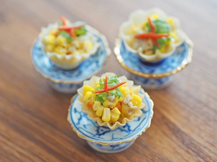 three small blue and white dishes filled with food on top of a wooden table next to each other