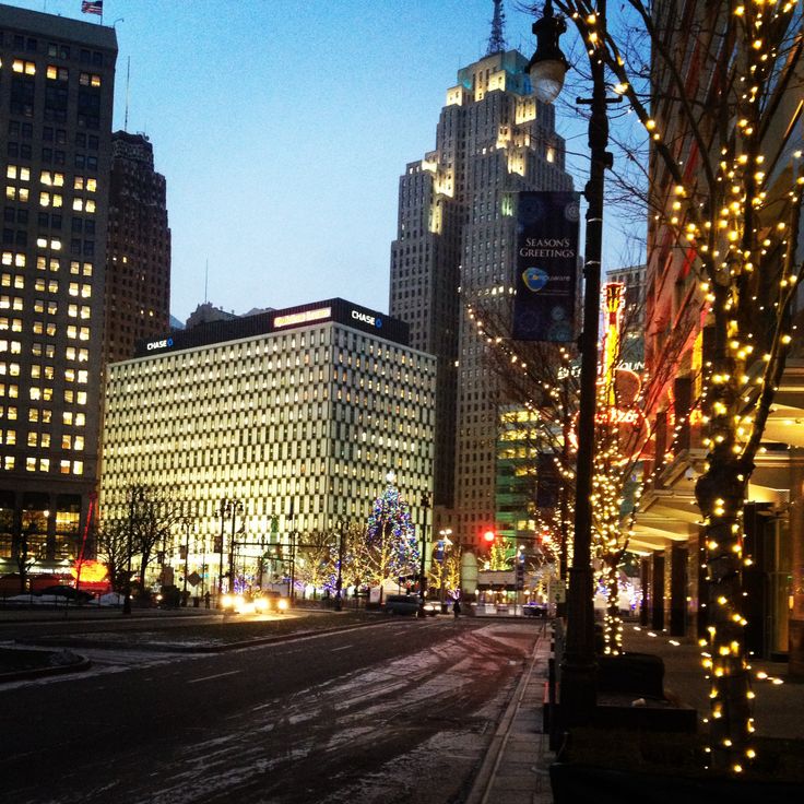 a city street is lit up with christmas lights and buildings are in the back ground