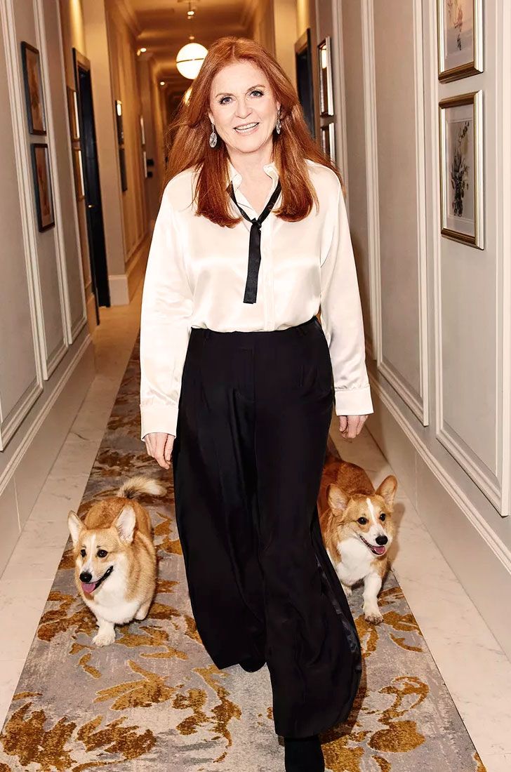 a woman is walking down the hallway with two corgis behind her on carpet