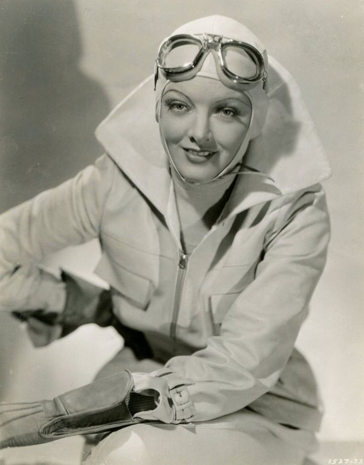 an old black and white photo of a woman with goggles on holding a pair of scissors