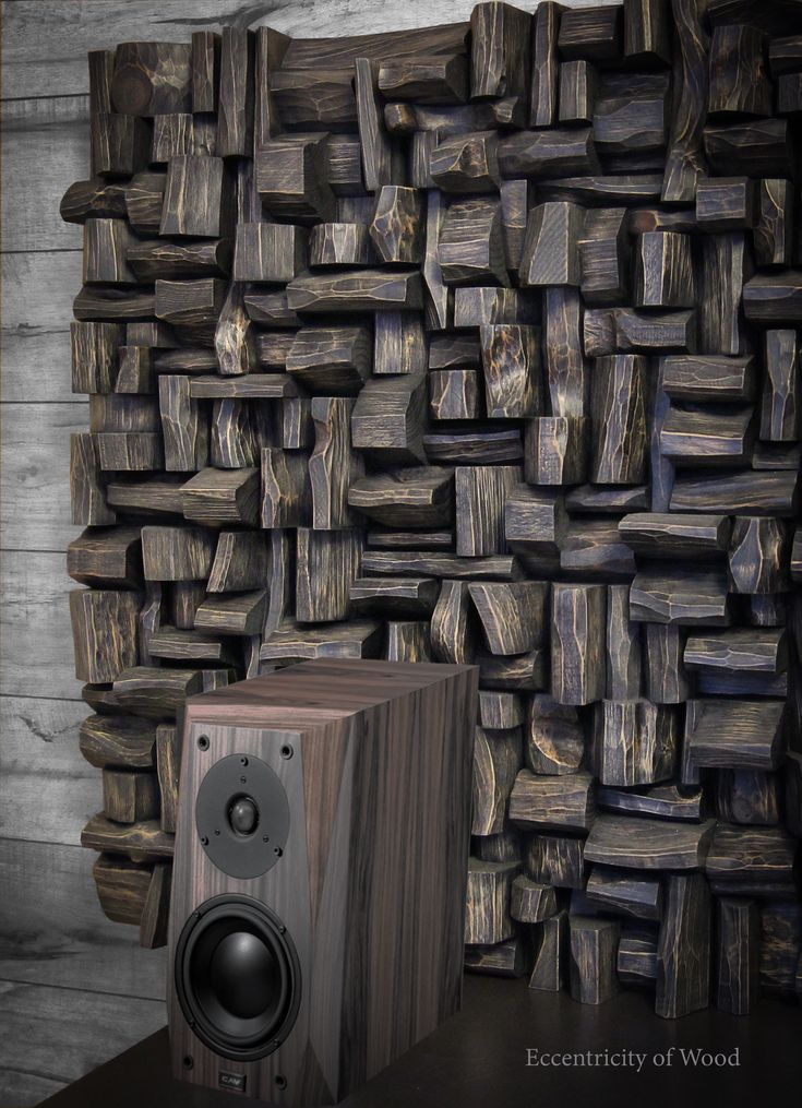 a wooden speaker sitting next to a stack of wood planks in front of a wall