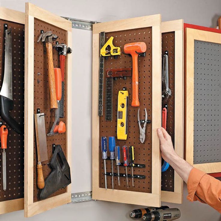 a man is holding an open cabinet with tools in it