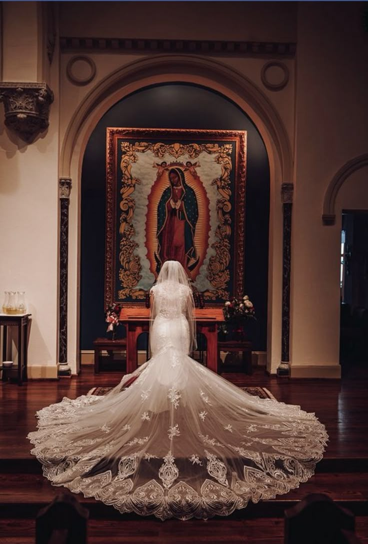 a woman in a wedding dress standing at the alter with her veil blowing in the wind