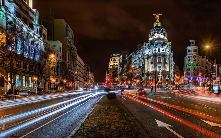 the city street is lit up at night with long exposure and blurry lights in the foreground