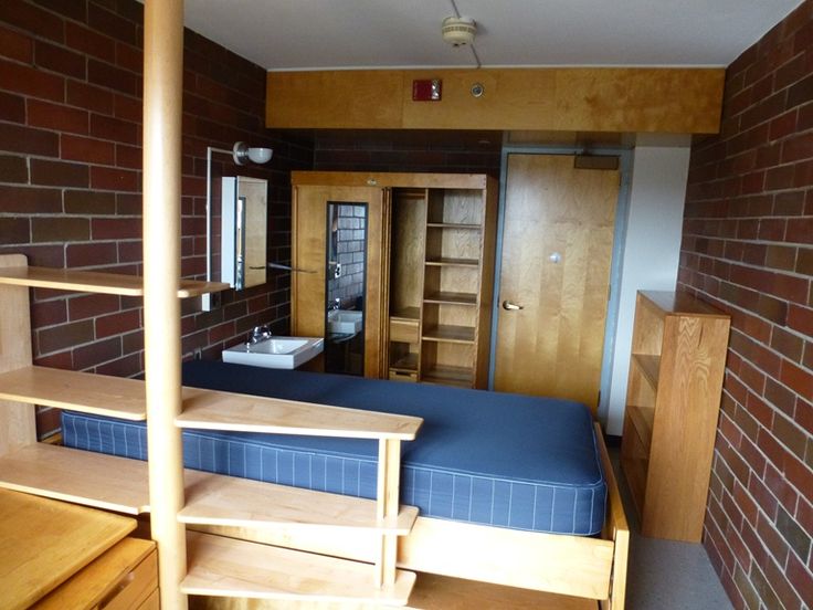 a room with a bed, desk and shelves on the wall next to each other