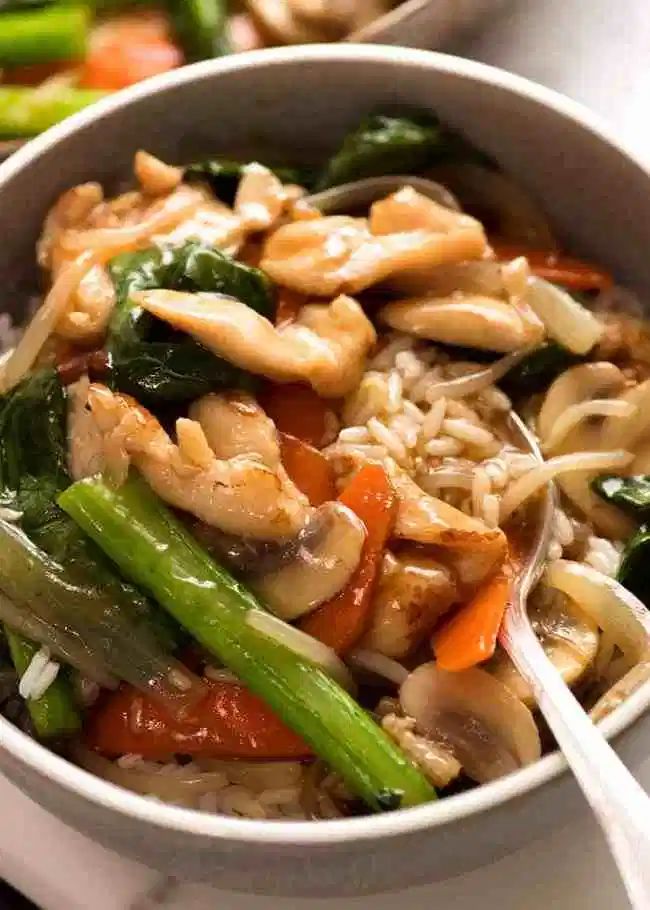 a close up of a bowl of food with rice and veggies on the side