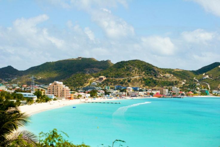 a beach with blue water and mountains in the background