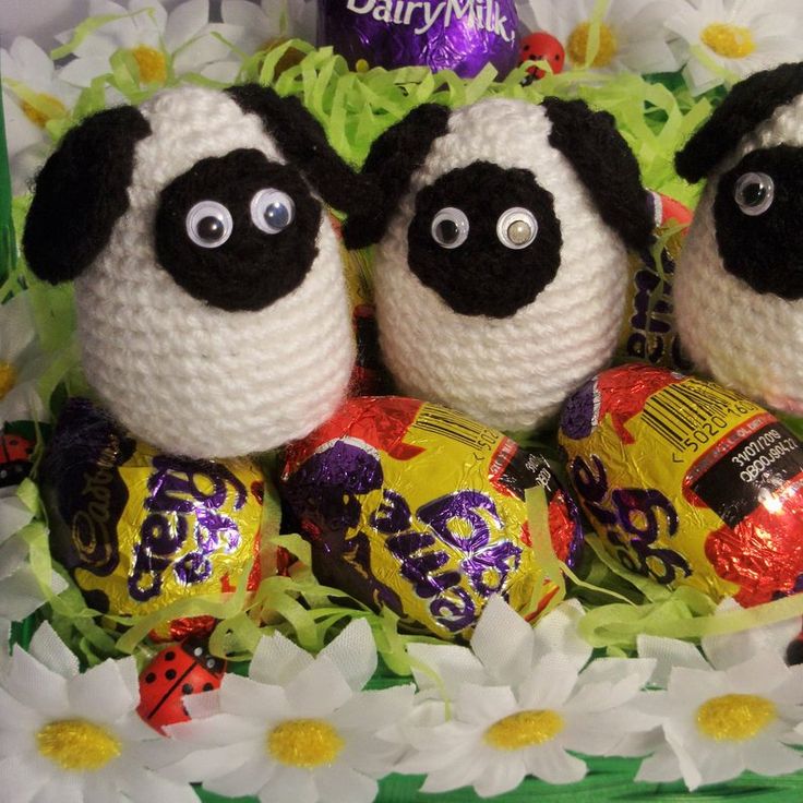 three crocheted stuffed animals sitting next to each other with candy in front of them