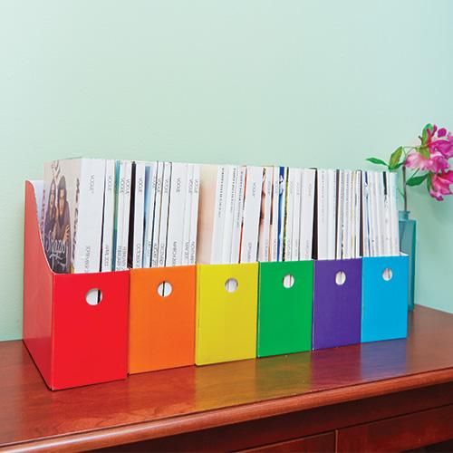 a row of binders sitting on top of a wooden desk next to a vase with flowers