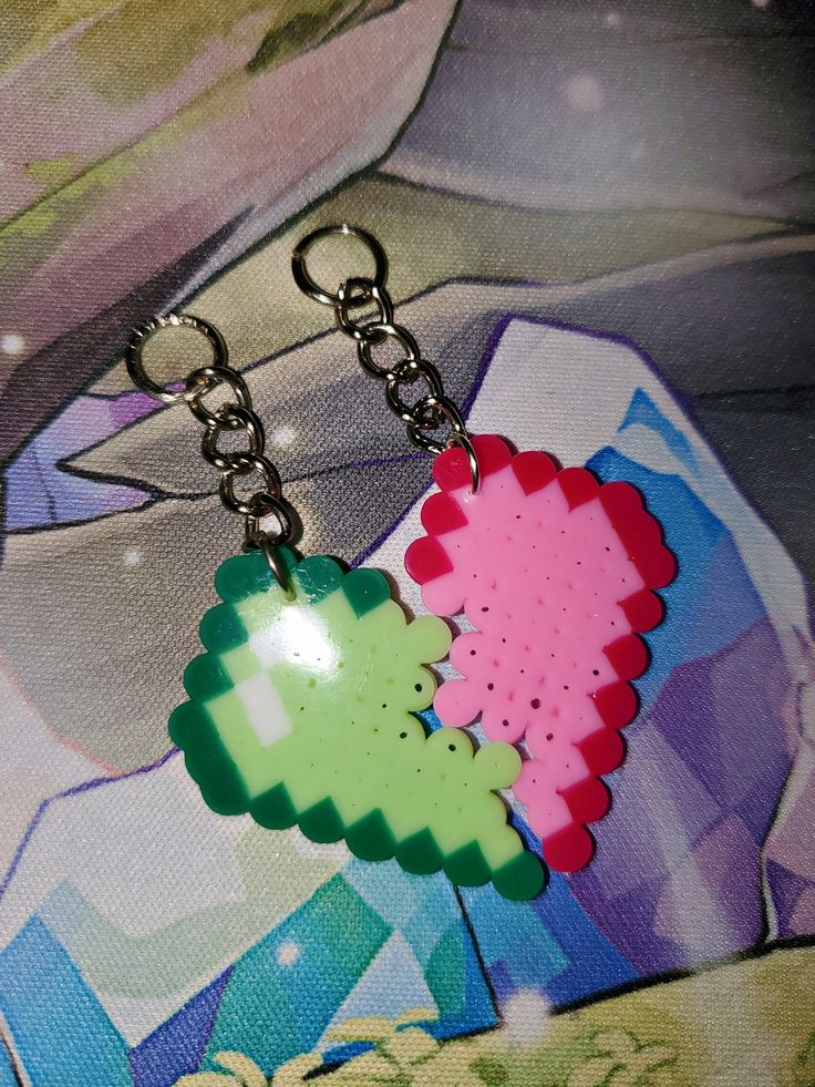 two pixel heart shaped keychains are on a piece of paper with chains attached to them