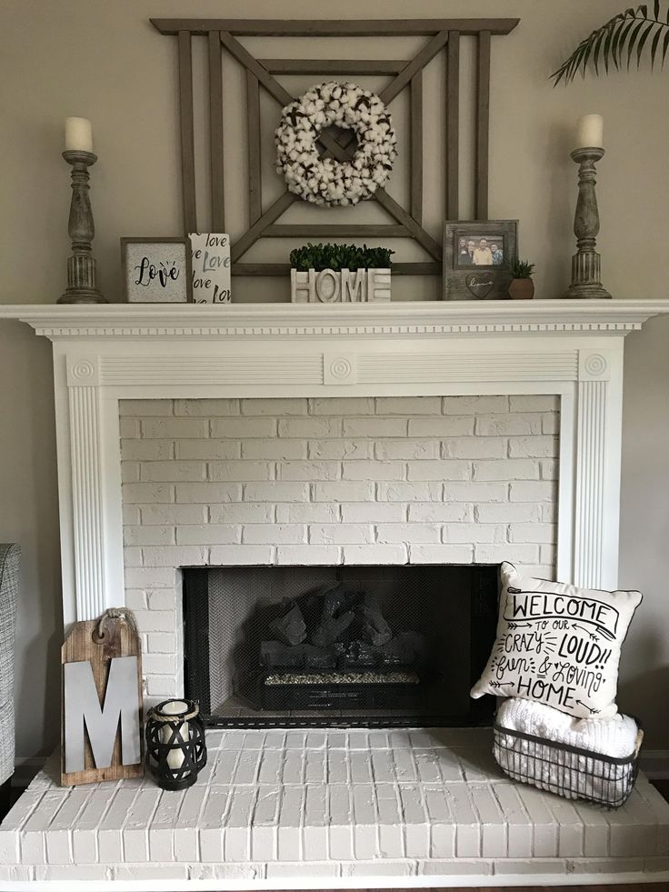 a white brick fireplace in a living room with wreaths on the mantel above it