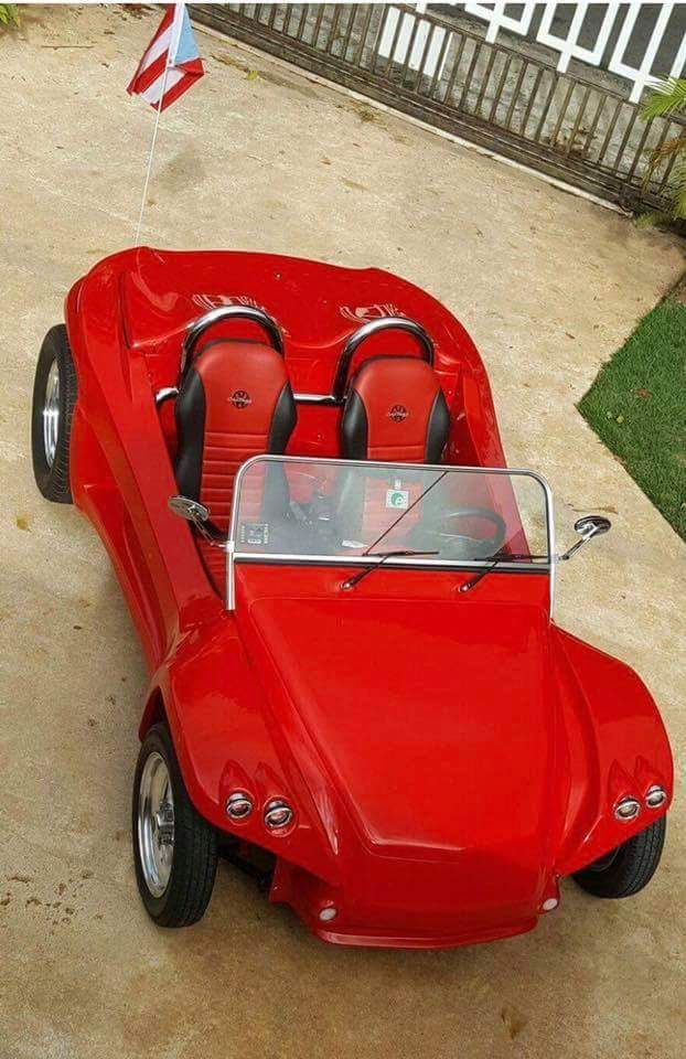 an old fashioned red car is parked in the driveway with two seats on it's side