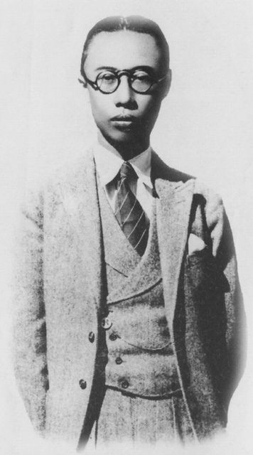 a black and white photo of a man in glasses wearing a suit with a tie