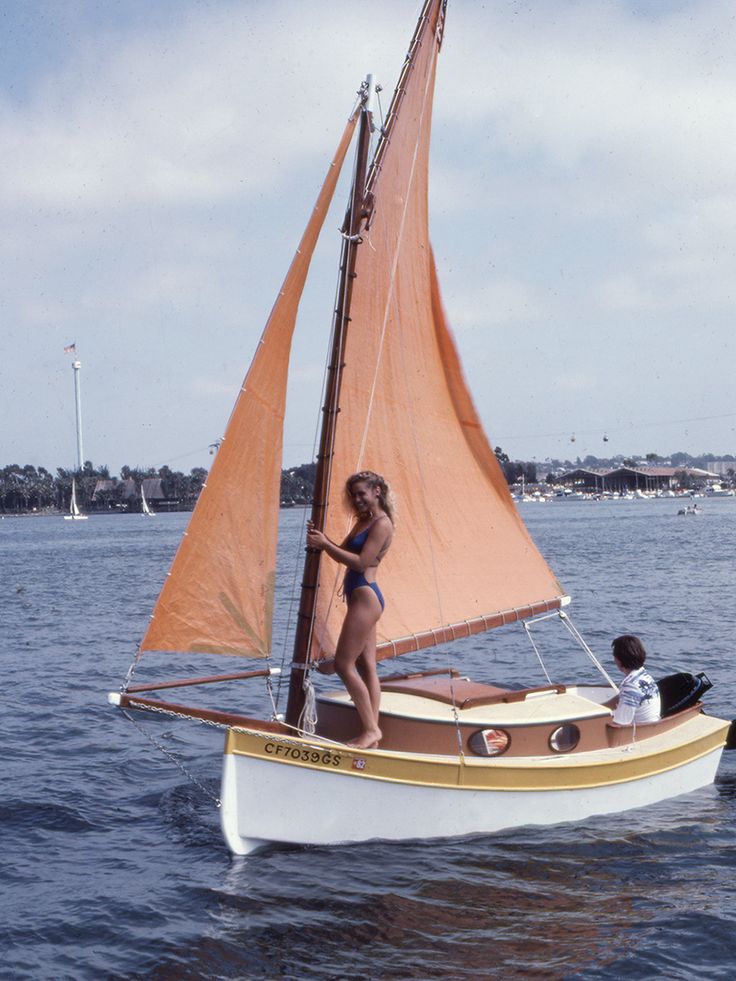 a woman standing on top of a sailboat in the water