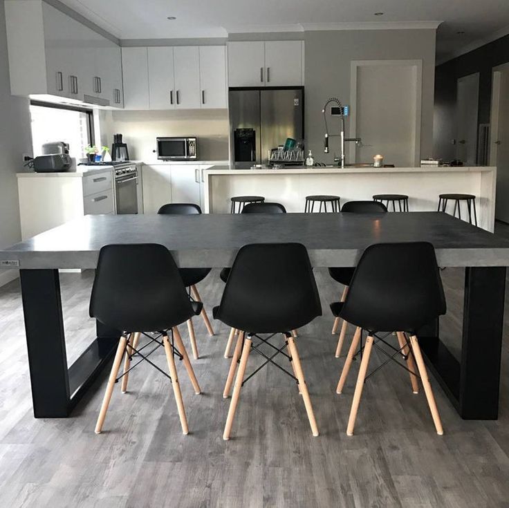 a table with four chairs in front of it and a kitchen area behind the table