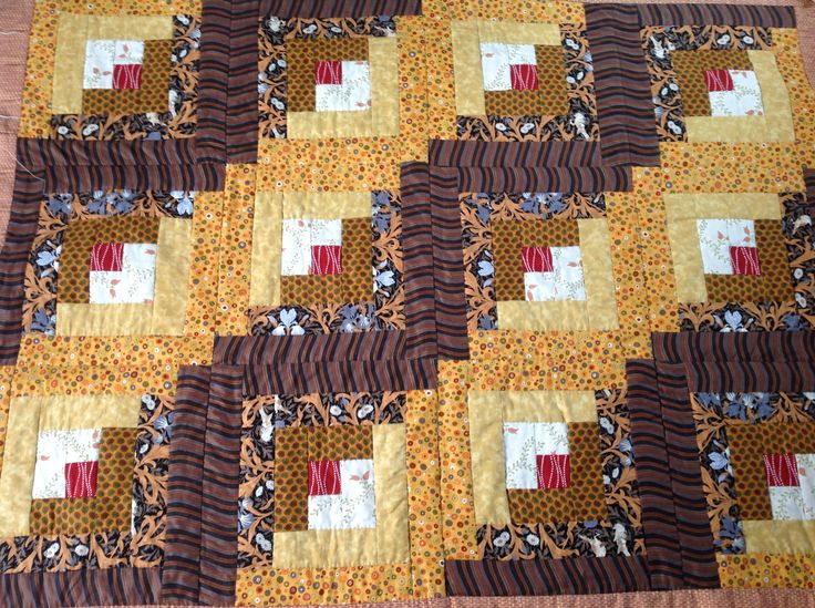 a close up of a quilt on a wooden floor with brown and yellow squares in the center