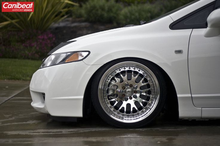 the front end of a white car with chrome rims