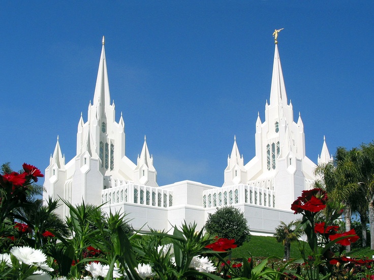 a large white building with many windows and flowers in the foreground