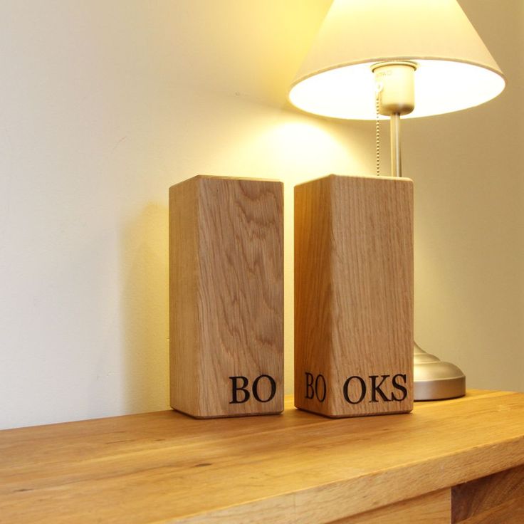 two wooden blocks with the words boo and oks on them sitting next to a lamp