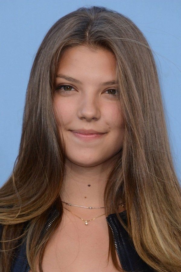 a close up of a person with long hair wearing a black jacket and smiling at the camera