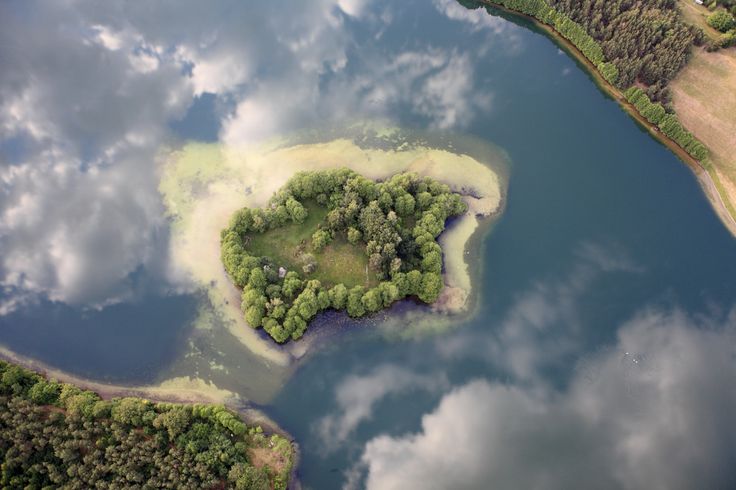 an aerial view of a small island in the middle of a lake surrounded by trees