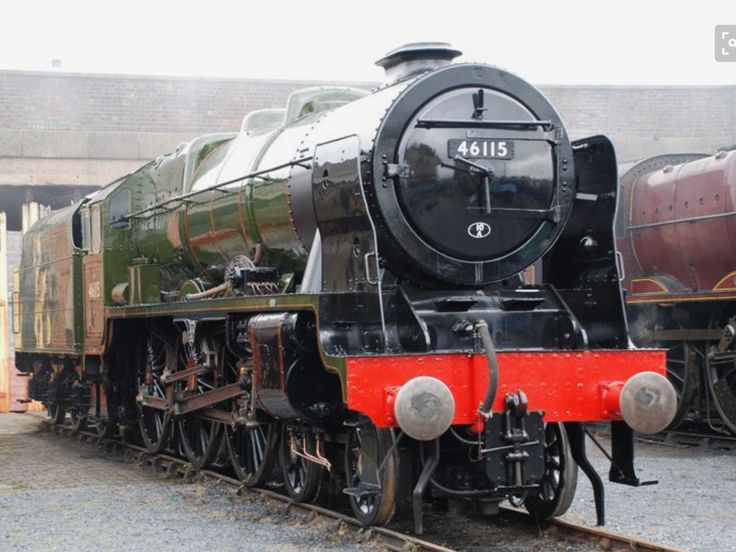 an old fashioned steam engine sitting on the tracks