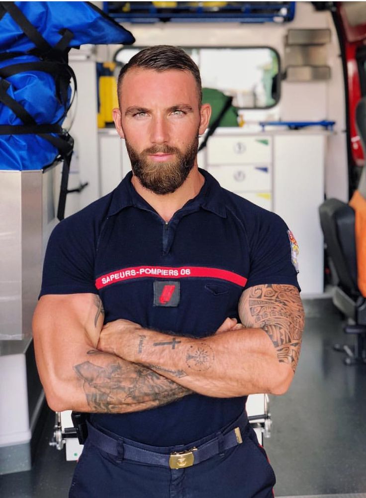 a man with his arms crossed standing in front of a fire truck