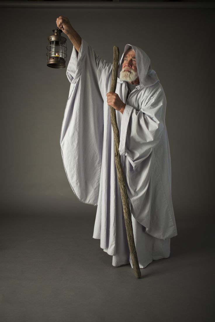 an old man in white robes holding a lantern