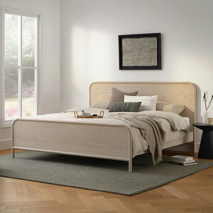 a white bed sitting on top of a hard wood floor next to a large window