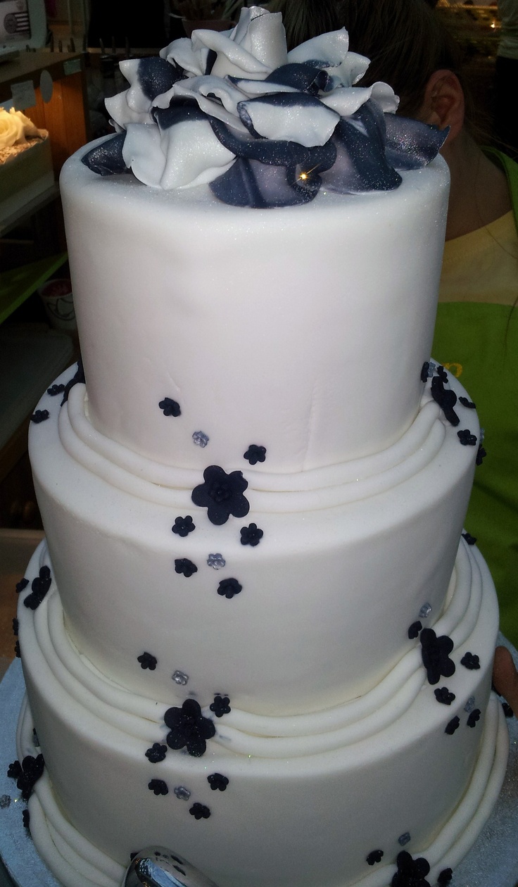 a three tiered white cake with black flowers on it