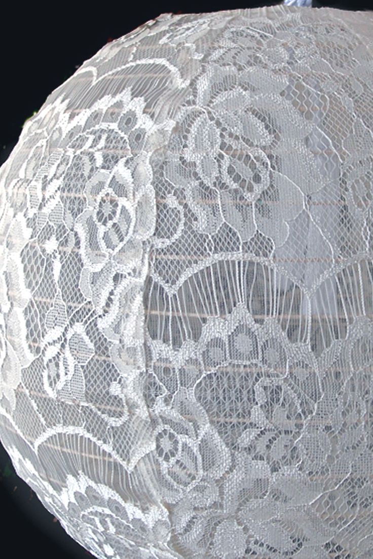 an old white lace doily is displayed on a mannequin's head