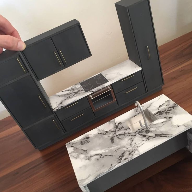 a kitchen with black cabinets and marble counter tops, in someone's hand over the sink