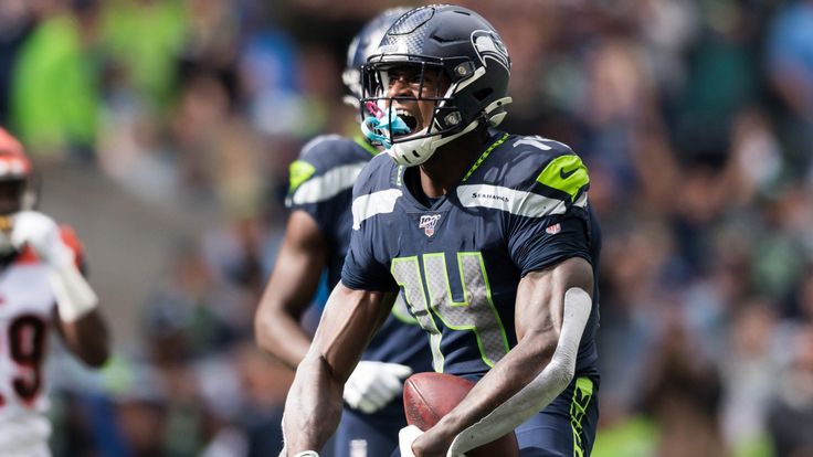 a football player holding a ball in his hand and running with the ball behind him