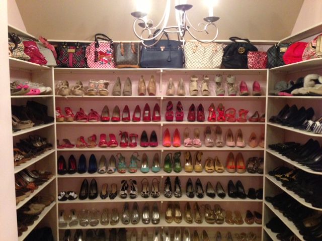 a closet filled with lots of shoes and purses next to a chandelier